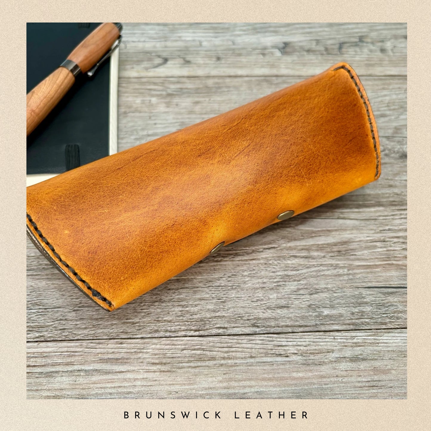 Brown leather case on a wooden surface with 'Brunswick Leather' branding.