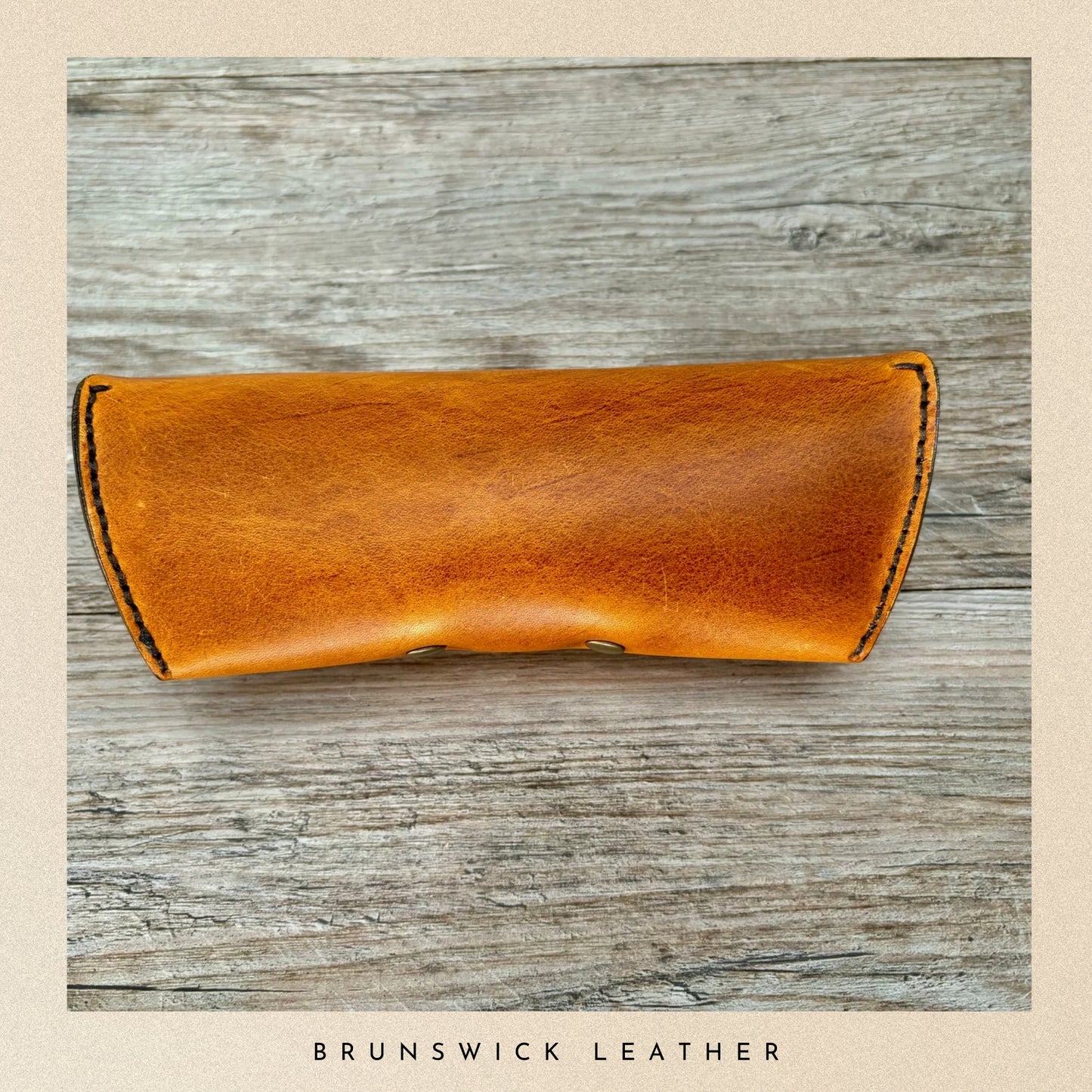 Brown leather case on a wooden surface with 'Brunswick Leather' branding.