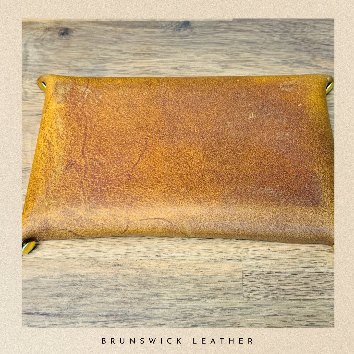 Brown leather pouch on a wooden surface with 'Brunswick Leather' branding.