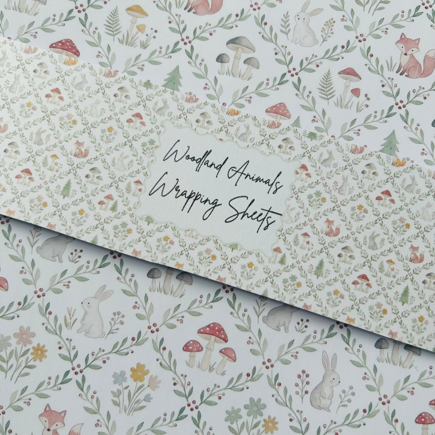 Woodland animals wrapping sheets with fox, rabbit, and mushroom design on a light green background.