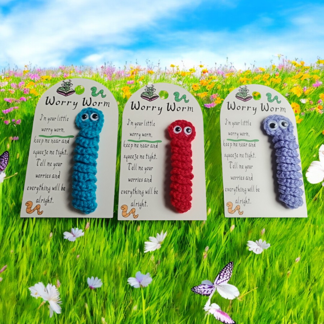 Three worry worms on cards with a poem against a grassy background