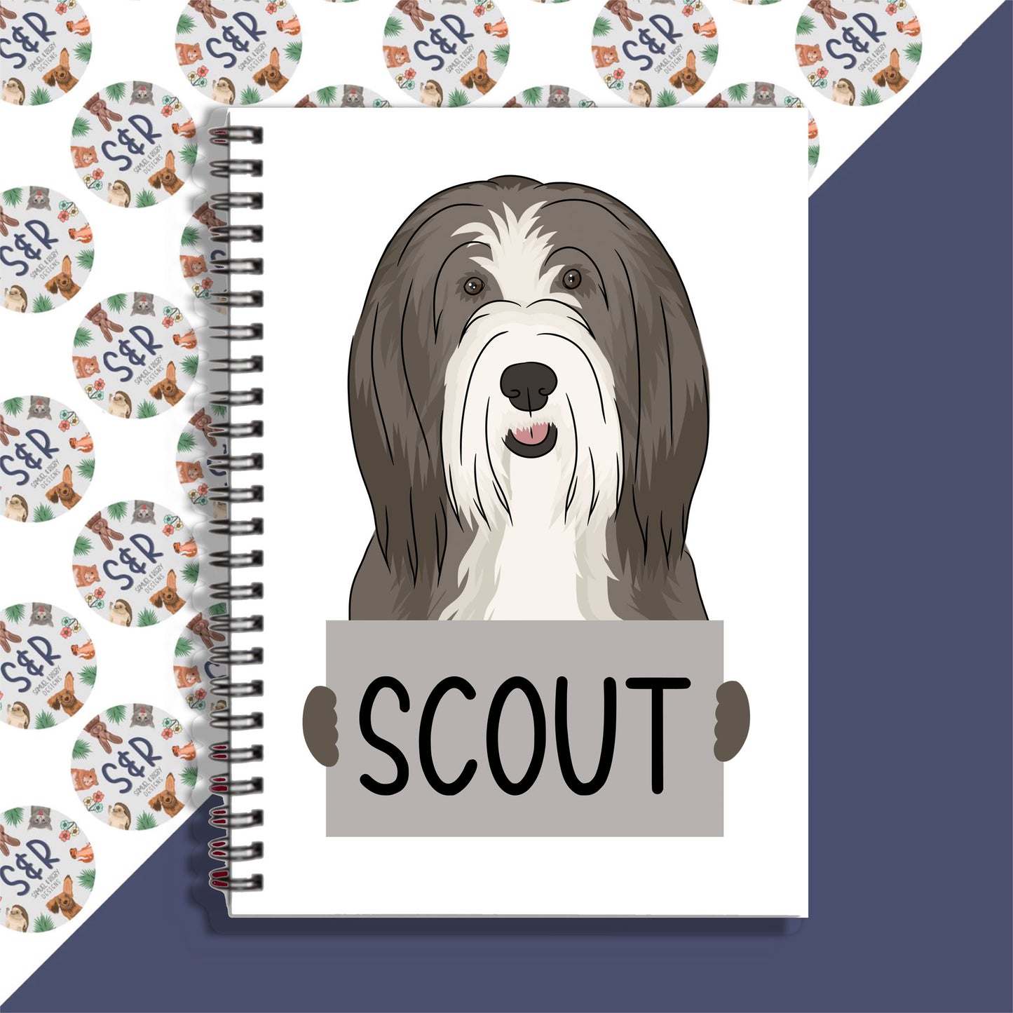A personalised notebook with a graphic of a bearded collie dog on the cover, labeled 'SCOUT'.