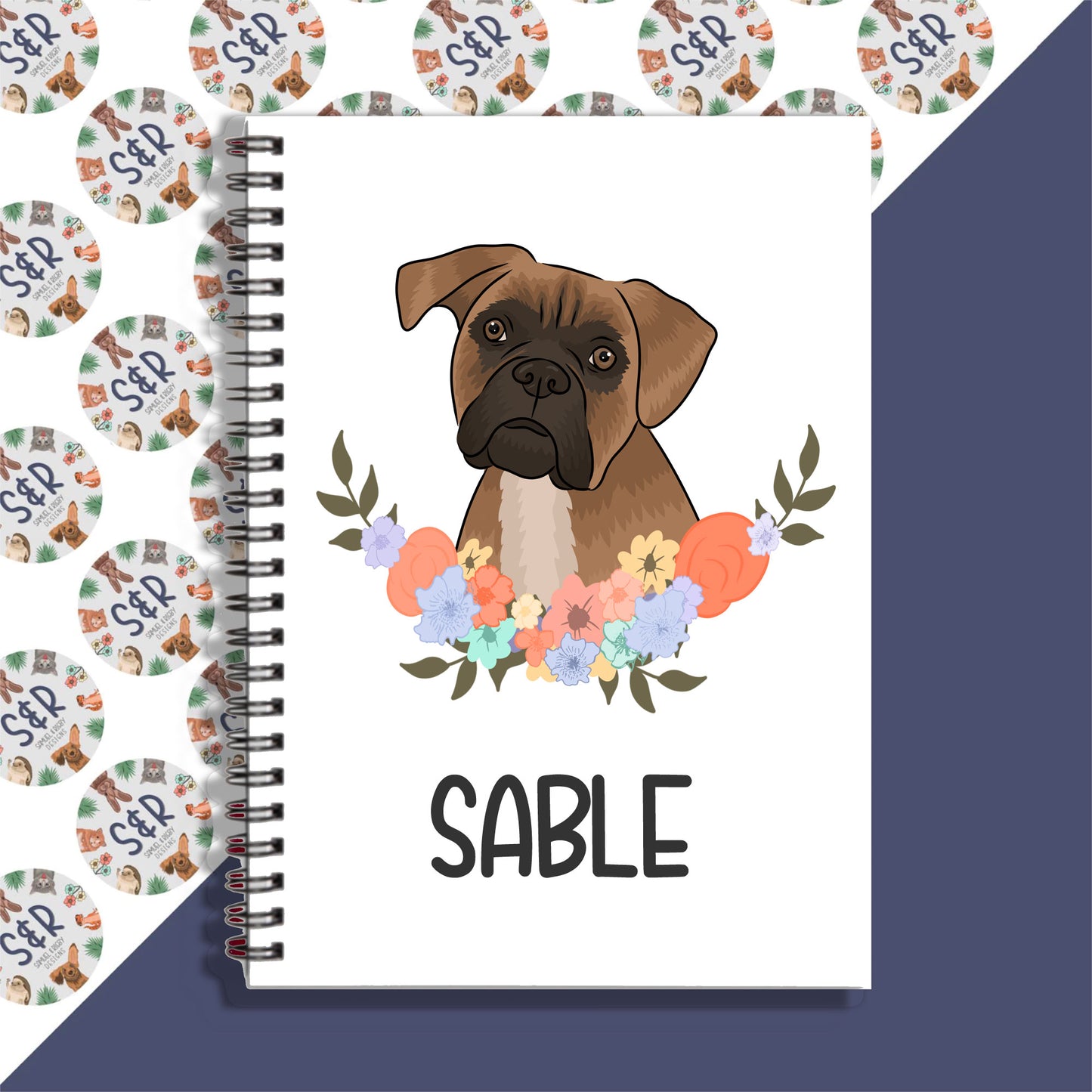 A personalised notebook with a spiral binding featuring a graphic of a boxer dog with a floral wreath on the cover.