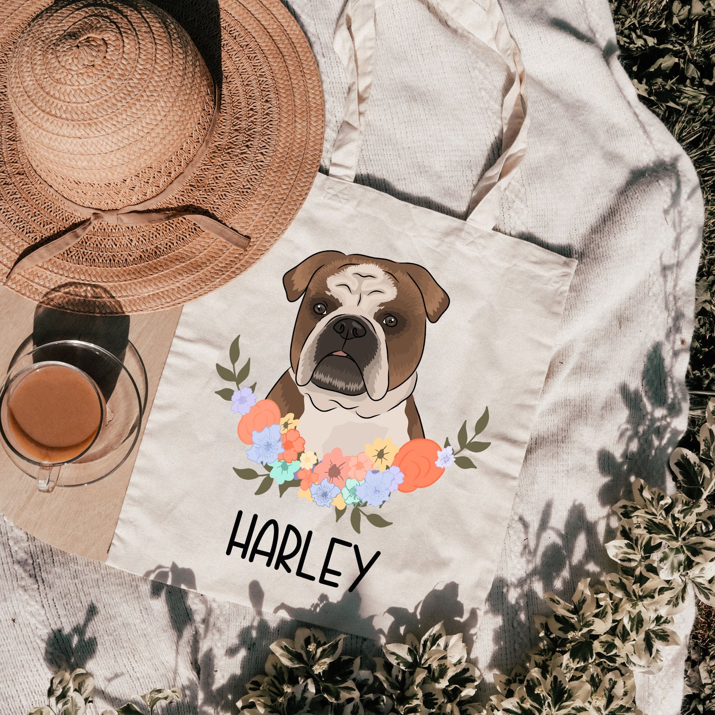 A white tote bag with a printed image of a bulldog surrounded by a floral wreath, with the name 'Harley' printed below the image.