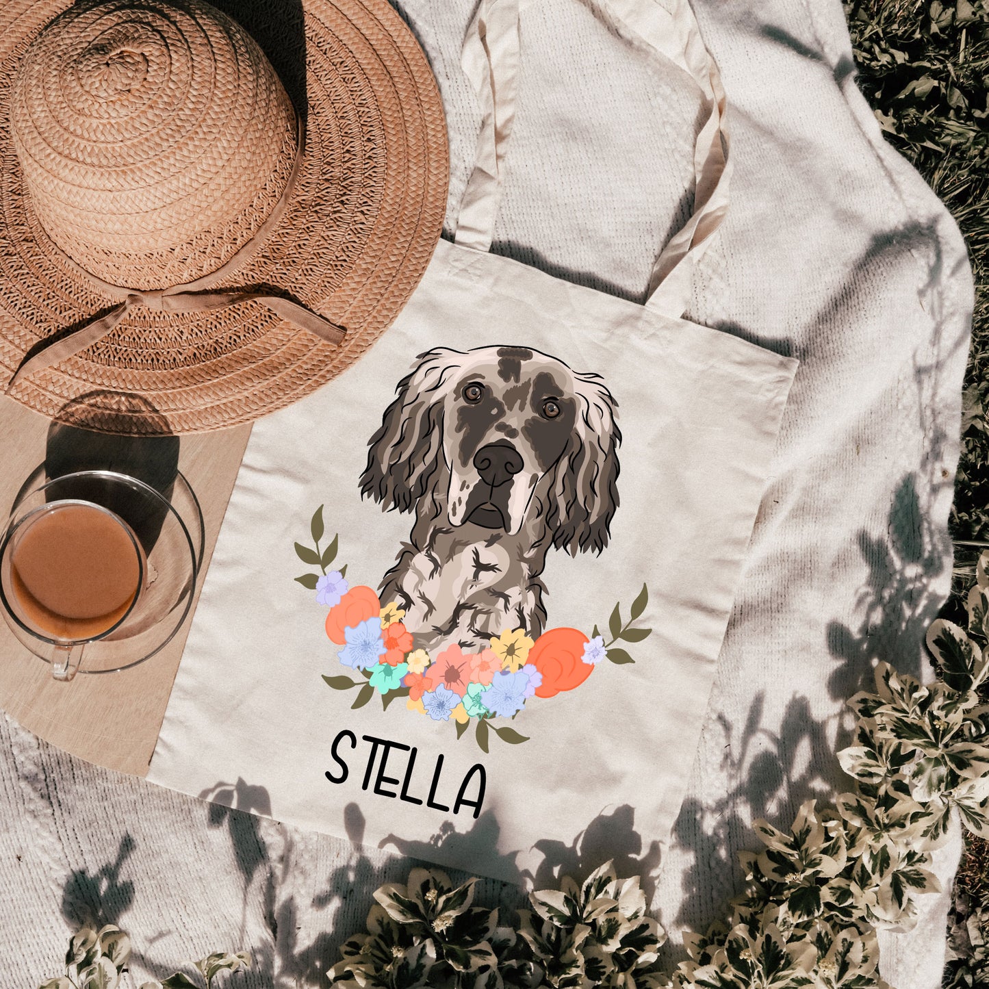 A white tote bag with a personalised print of an English Setter dog surrounded by a floral wreath, with the name 'Stella' printed on the bag.