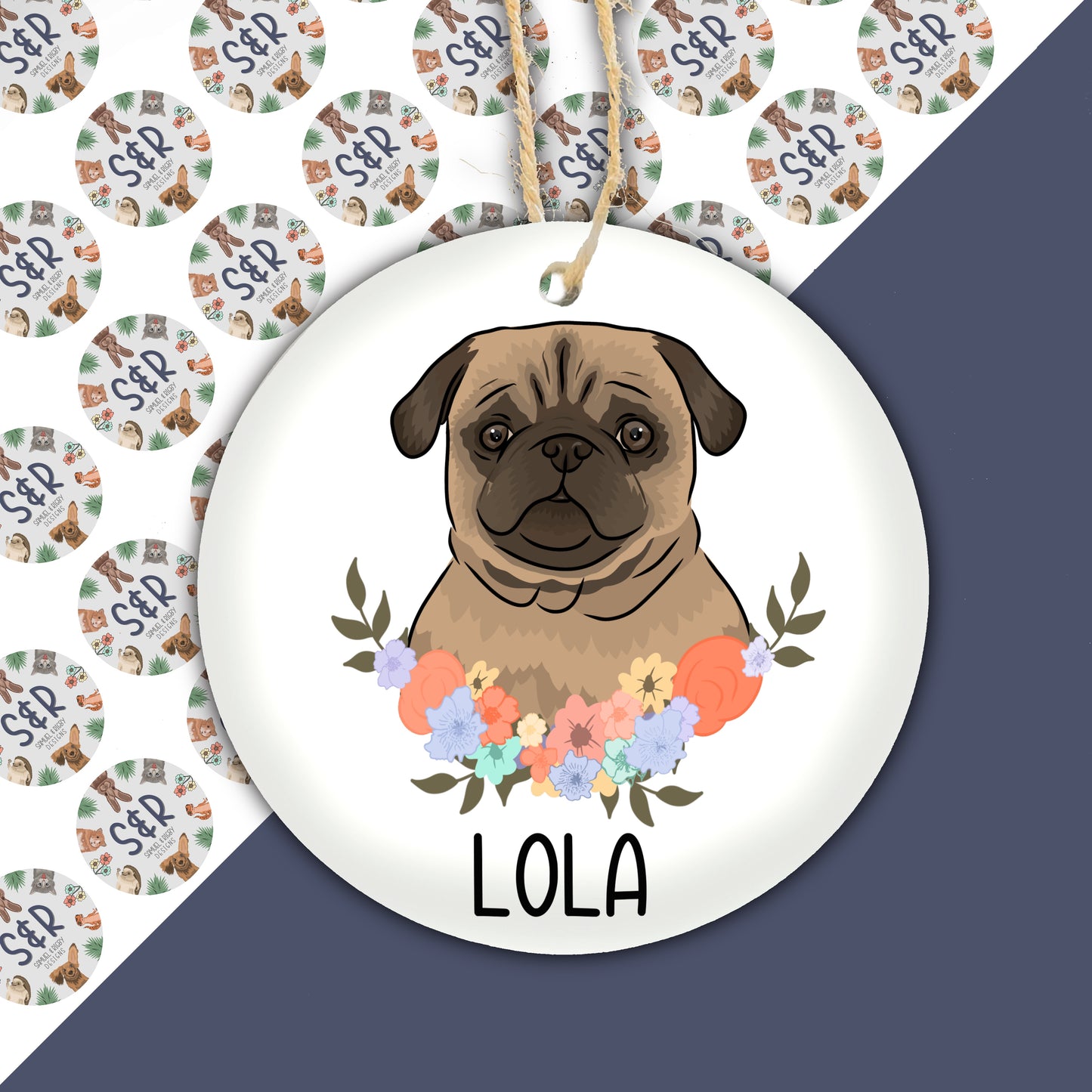 A round ceramic Christmas decoration featuring an illustration of a Pug dog with a floral wreath background, with the name 'LOLA' at the bottom.