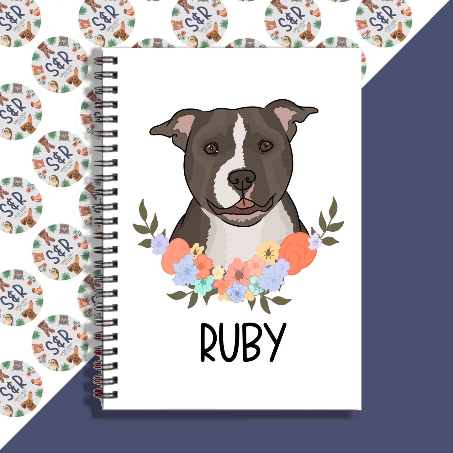 A personalised notebook with a spiral binding featuring an illustration of a dog on the front cover, with the name 'Ruby' written on the notebook.