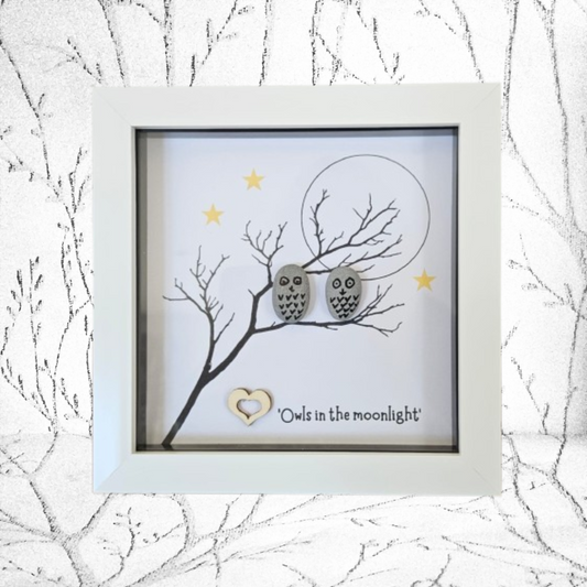 Framed artwork with pebble owls on a branch against a moon and star background.
