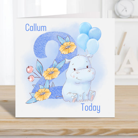Boy birthday card age 2 years. Personalised with a name. Blue number with floral decoration. Blue hippo and balloons.
