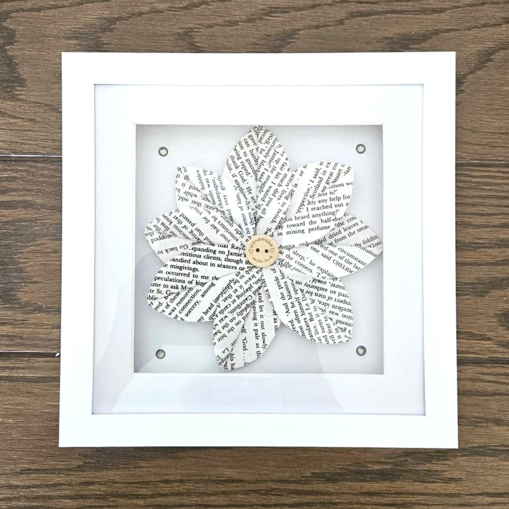 Framed paper flower made from text on a wooden surface