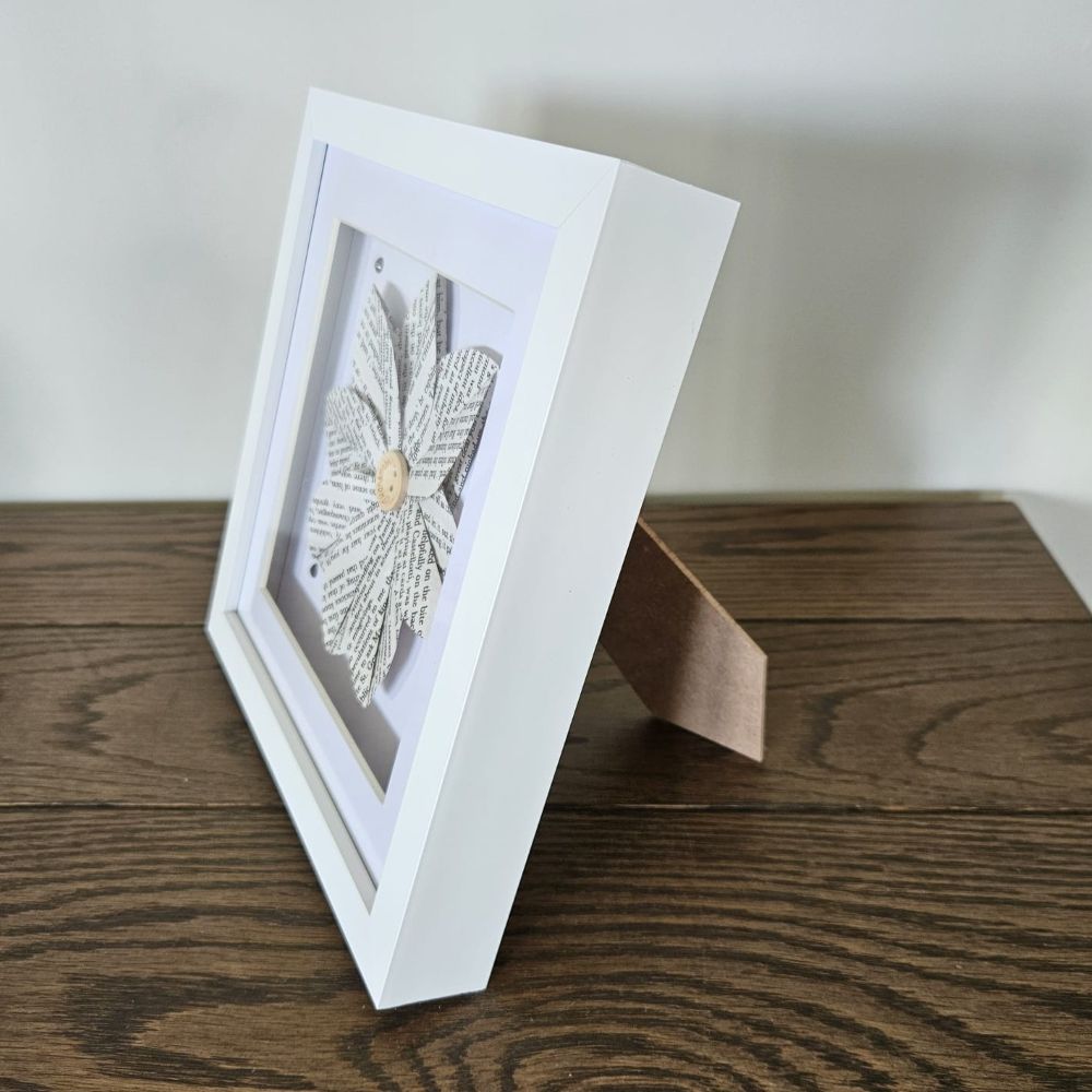 White photo frame with a decorative item on a wooden surface