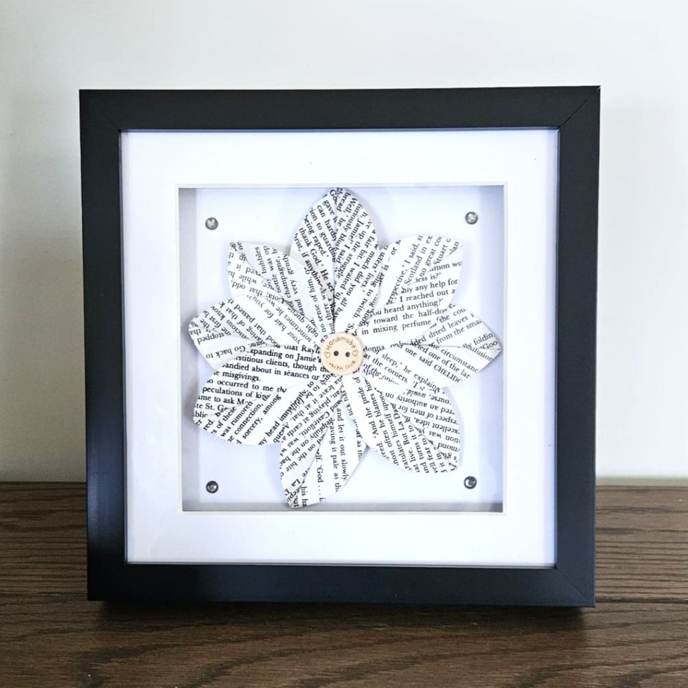 Framed artwork with a flower design made of text on a white background