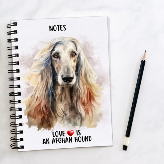 White spiral bound notebook showing a head shot of an Afghan Hound with flowing hair facing forward and a quote written at the bottom. A black pencil is placed to the right hand side.