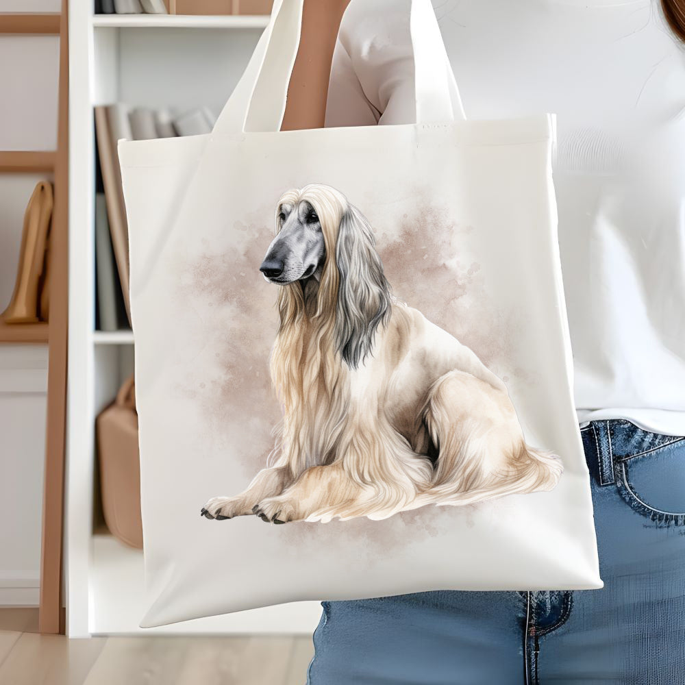 White long handled tote bag showing a cream Afghan Hound sat facing left. A smoky brown background decorates. A woman is holding the bag  in front of white book case.