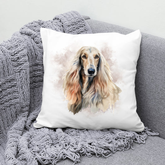 Afghan Hound head shot facing forward with a smokey brown background on a white Cushion.  The cushion is placed in a the corner of a grey sofa with a grey knitted blanket draped across the corner.