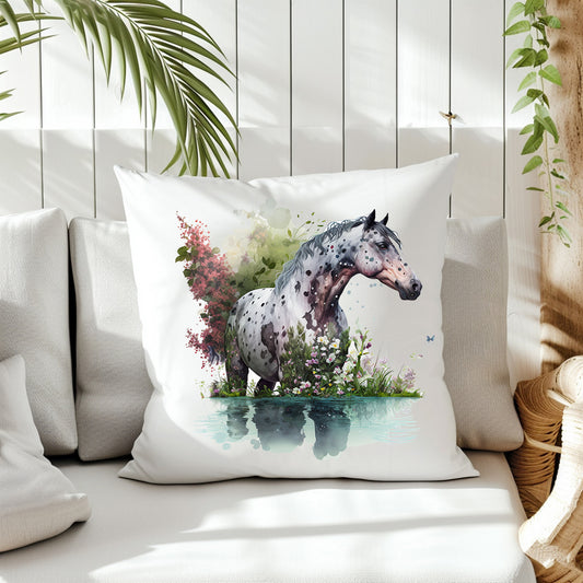 An Apaloosa Horse standing in water looking to the right.  Pink and white flowers decorate the background on the front of a white cushion which is placed on a cream sofa.  White panels and green fern create the background.