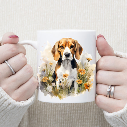 A Beagle dog sits among orange and white flowers on a white ceramic mug which is being held by a woman.