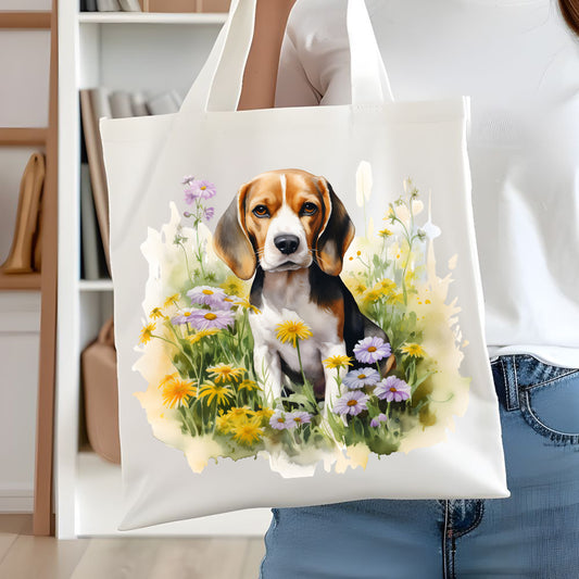 White tote bag with a long handle showing a Beagle dog sitting in a field of purple and yellow flowers. A woman is holding the bag in front of white book case.