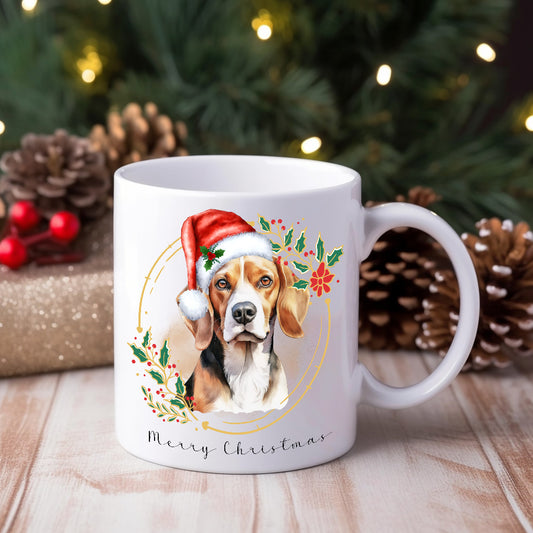 A white ceramic mug with a watercolour design of a beagle wearing a Santa hat, placed on a wooden surface with Christmas decorations around.