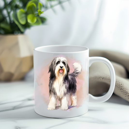 Bearded Collie in a sitting position on a white ceramic mug which has been placed on a grey marble surface. A plant decorates the left corner.
