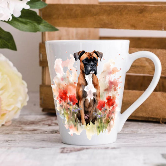 A white ceramic latte coffee mug with an illustration of a Boxer dog surrounded by floral elements, positioned on a wooden surface with a blurred background.
