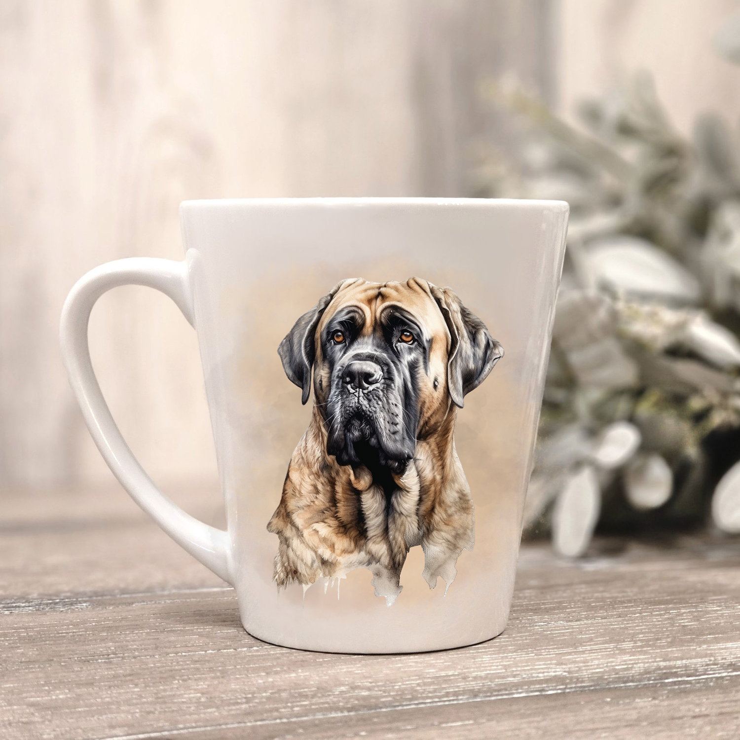 A Bullmastiff is shown on a white ceramic latte mug in a smoky background.  The mug is placed on a wooden surface with sage green foliage to the right-hand side.