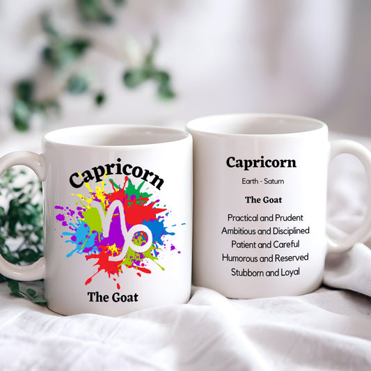 Two white ceramic coffee mugs with colorful astrological sign Capricorn symbol and traits printed on them, placed on a surface with a plant in the background.