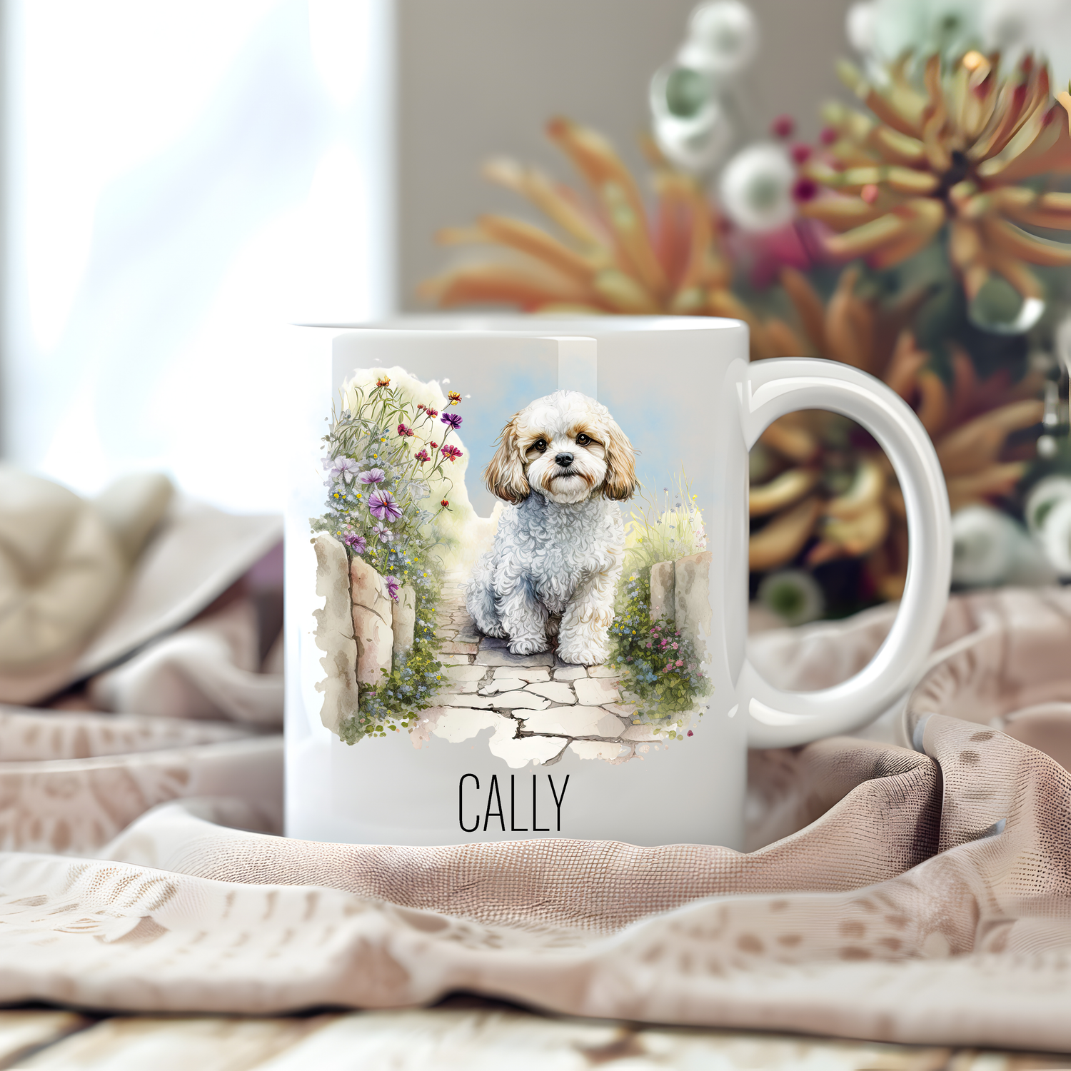 Personalised coffee mug featuring a seated Cavachon on a white ceramic mug which has been placed on a beige cloth.  Stems of large  flowers accessorizes the image.