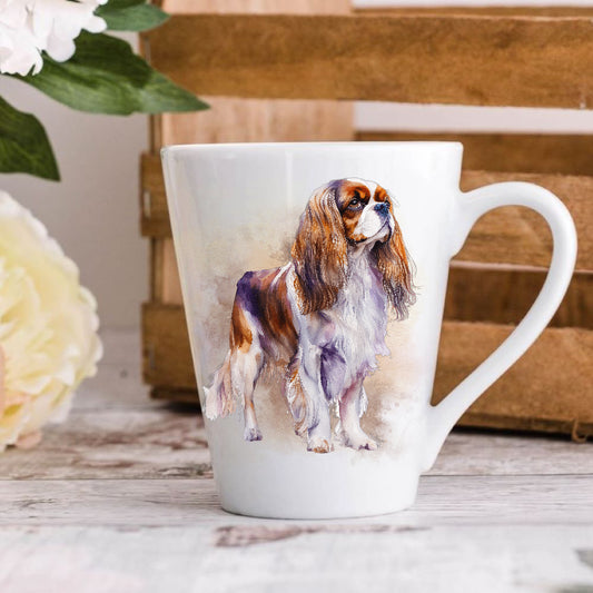 A ceramic latte coffee mug featuring an illustration of a Cavalier King Charles Spaniel dog, with a wooden background and a white floral pattern on the mug.