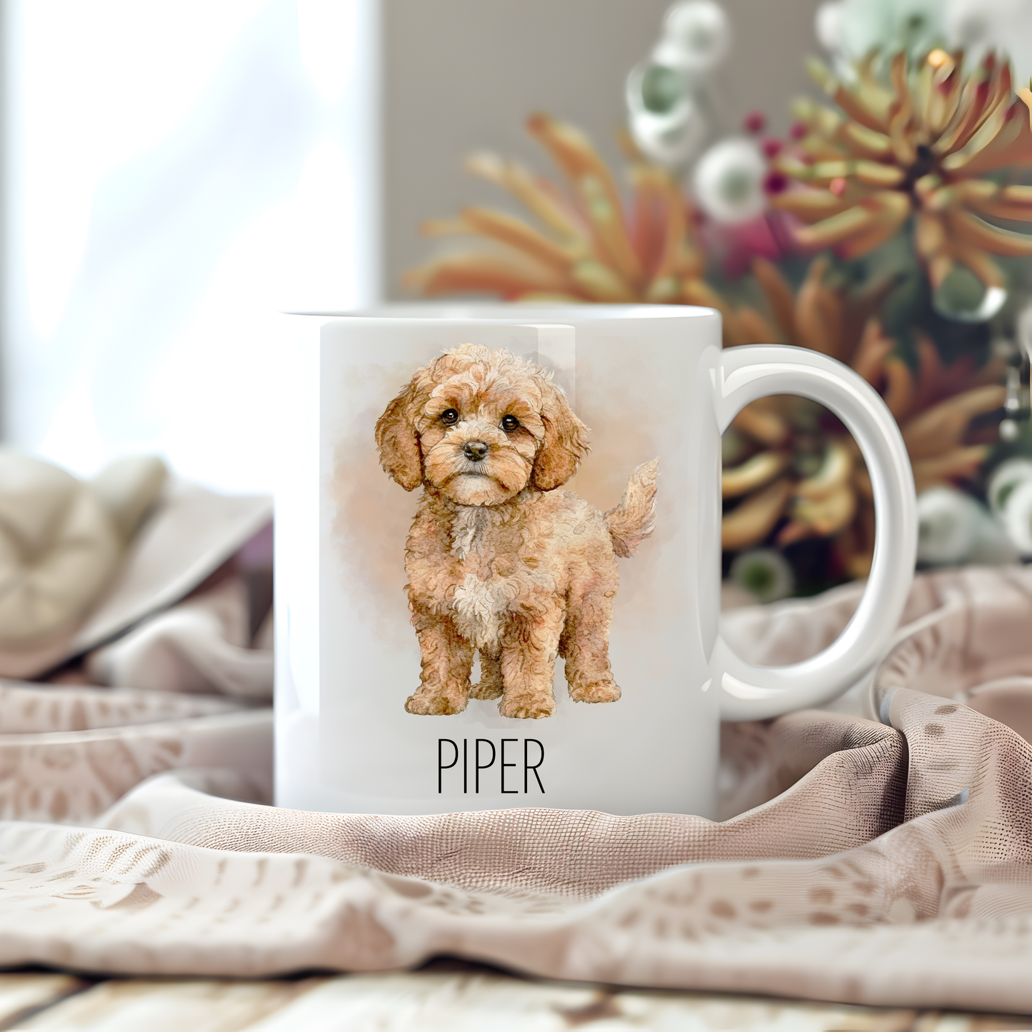 Personalised coffee mug featuring a standing Cavapoo on a white ceramic mug which has been placed on a beige cloth.  Stems of large  flowers accessorizes the image.