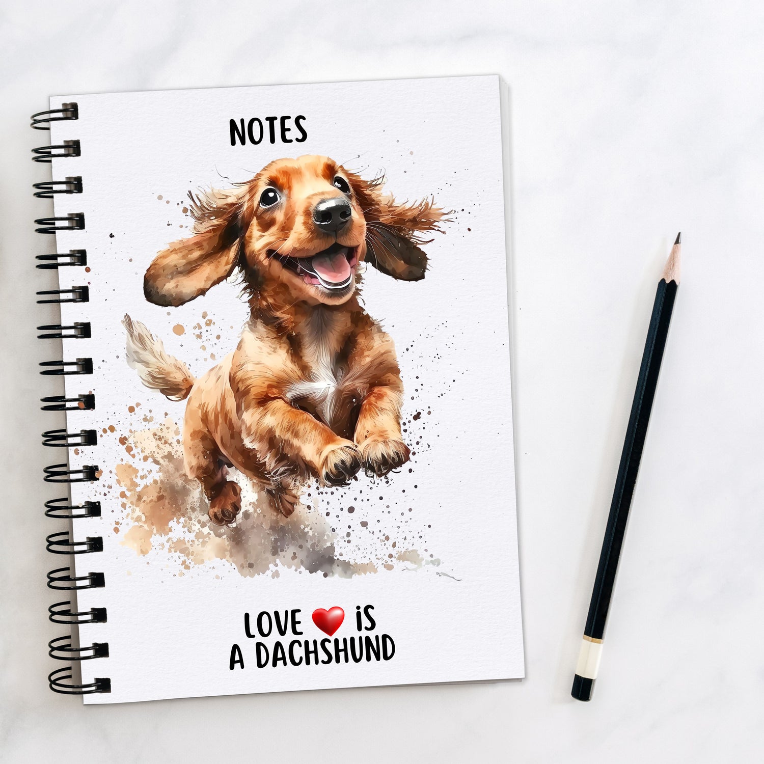 A5 white spiral bound notebook with a playful Dachshund on the front.  Black wire binding and a black pencil to the right hand side.  A quote with a red heart is placed at the bottom of the book.