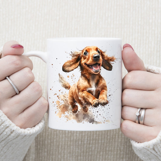White ceramic mug with a happy Dachshund running and splashing. The mug is being held by a woman with both hands.