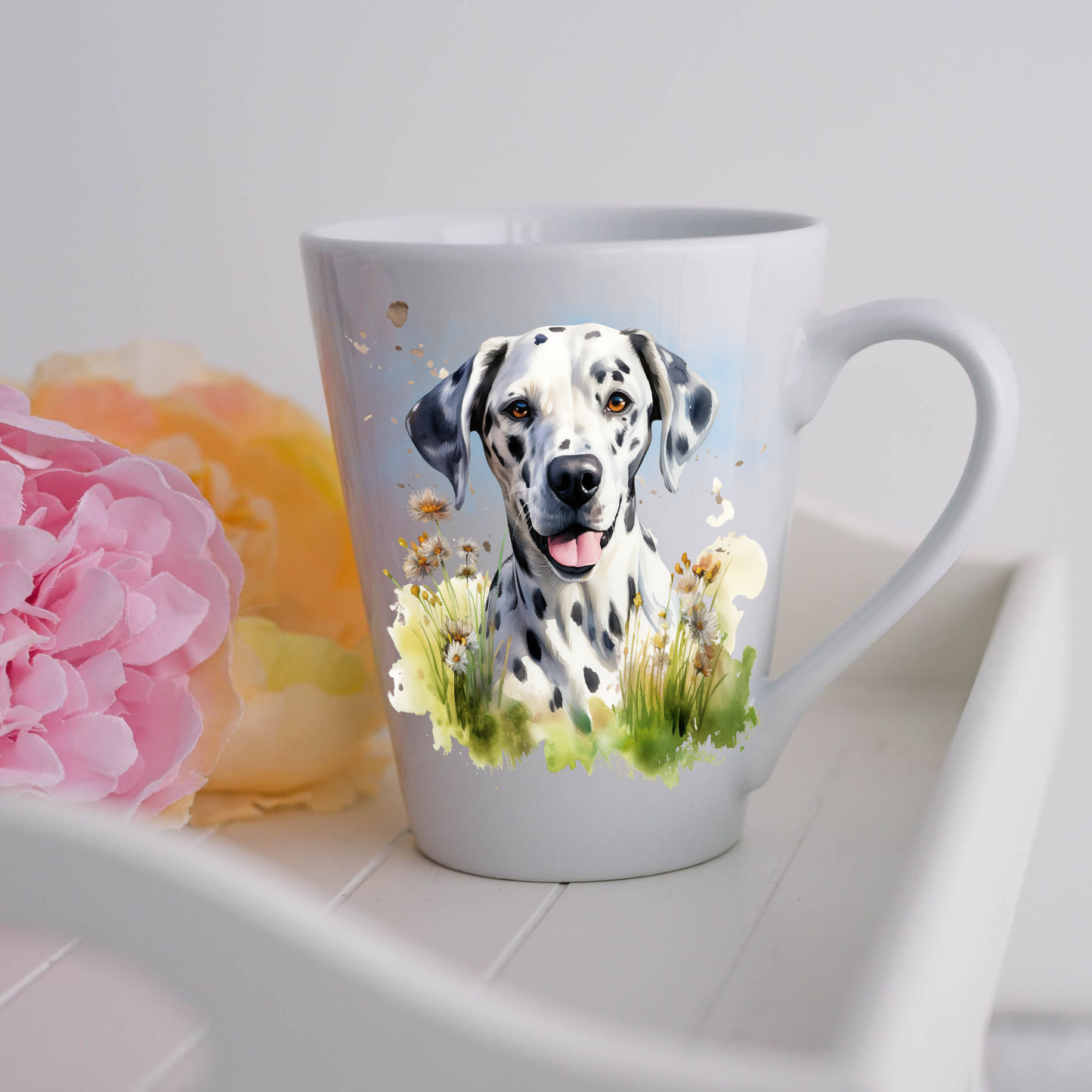 A Dalmatian is shown sitting among wildflowers on a white ceramic latte mug.  The mug is placed on a white tray with pink and yellow flowers. 