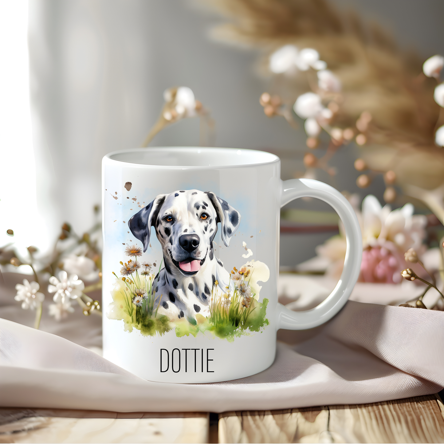 Dalmatian coffee mug personalised with a pet name.  The mug is sat on a wooden surface with a creamy coloured cloth and various flowers adorn the background.