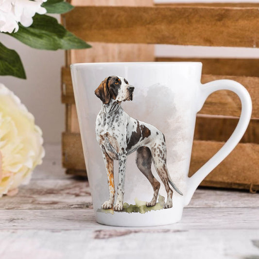 A 12oz white ceramic latte mug with a printed image of an English Pointer standing and looking right. Image has a blurred background.  Mug is positioned on a wooden surface.