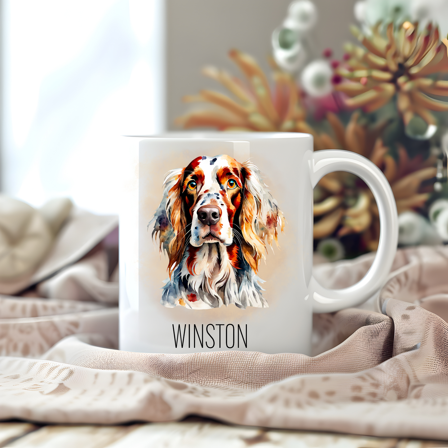 Personalised coffee mug featuring an English Setter on a white ceramic mug which has been placed on a beige cloth.  Stems of large  flowers accessorizes the image.