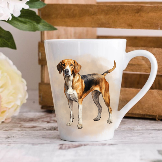 A white ceramic latte mug stands on a wooden surface with a crate in the background. The mug features a Foxhound. A large yellow flower peeps in from the left-hand side.