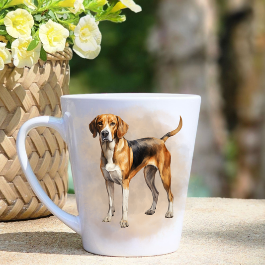 A white ceramic latte mug featuring a standing Foxhound in a beige smoky mist background.  A basket containing yellow flowers sits to the left-hand side.