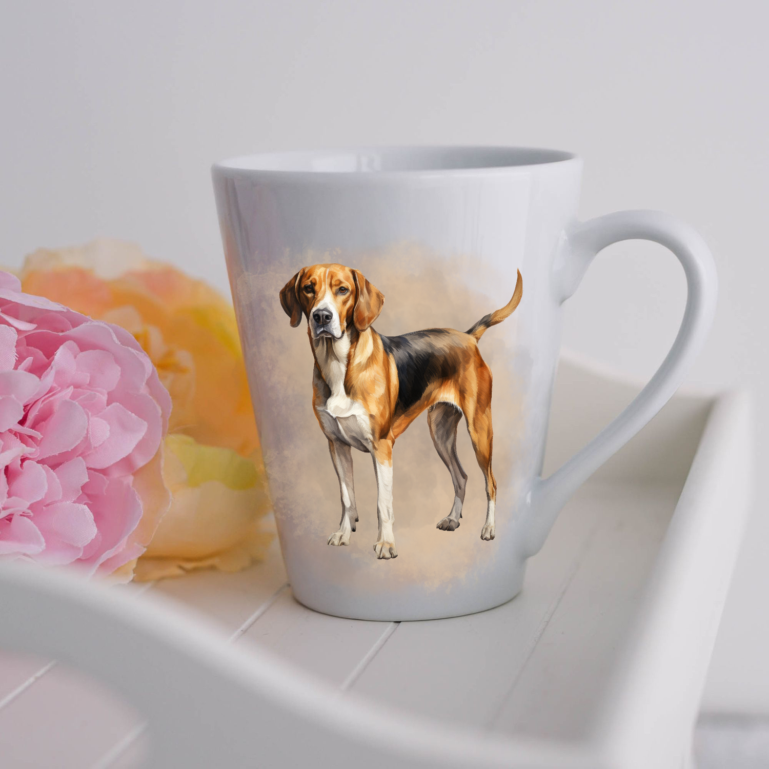 A beautiful Foxhound is shown standing on a white ceramic latte mug in a smoky background and looking forward.  The mug is placed on a white tray with pink and yellow flowers. 