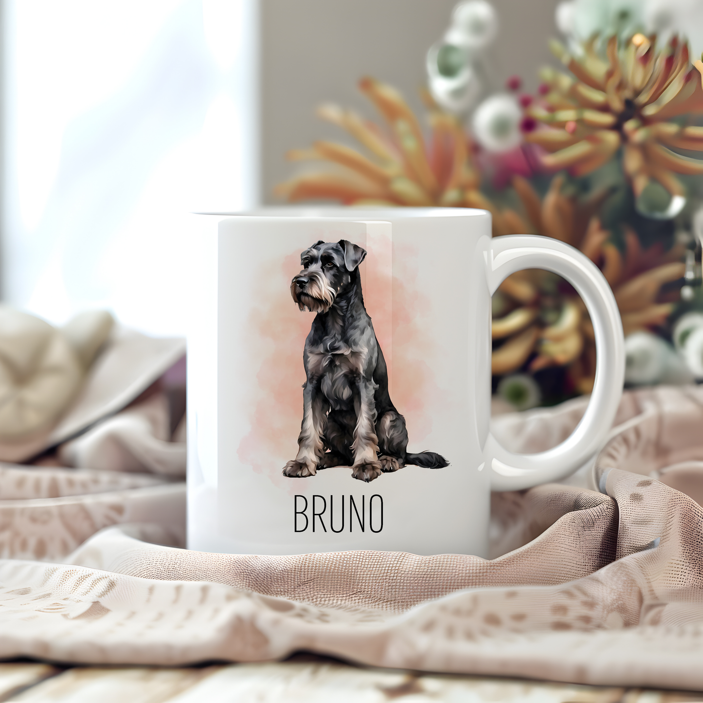 A personalised coffee mug featuring a seated Giant Schnauzer on a white ceramic mug which has been placed on a beige cloth.  Stems of large flowers accessorizes the image.