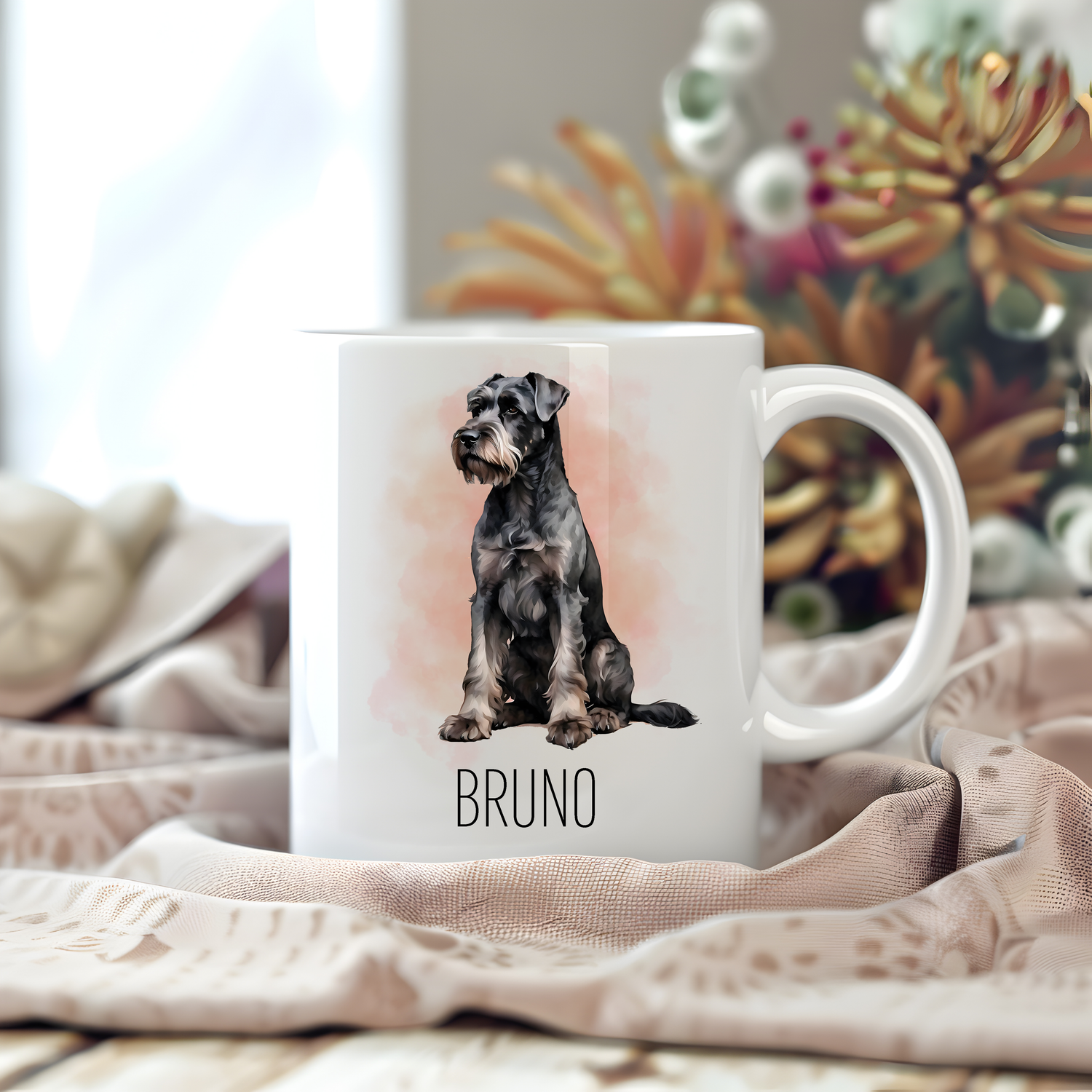 A personalised coffee mug featuring a seated Giant Schnauzer on a white ceramic mug which has been placed on a beige cloth.  Stems of large flowers accessorizes the image.