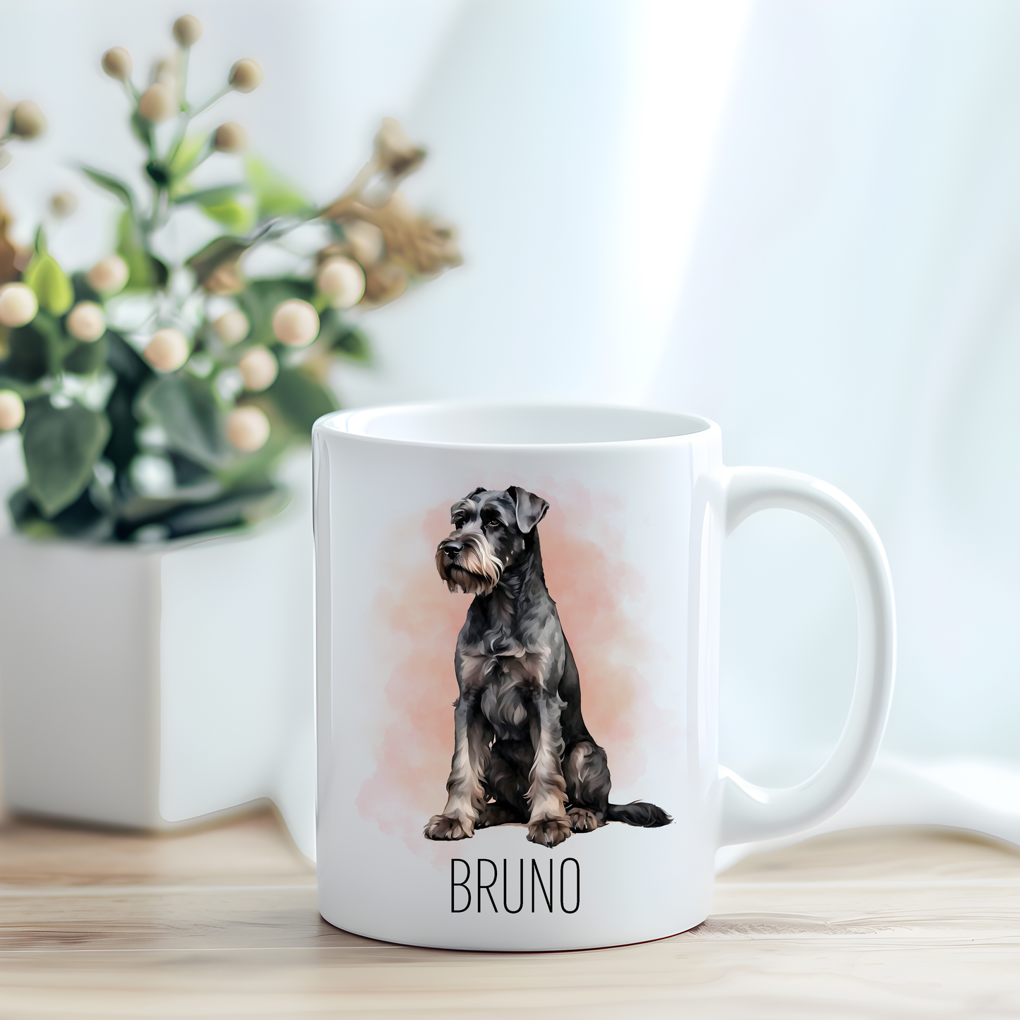 This coffee mug features a Giant Schnauzer on a white ceramic mug which has been placed on a light wooden surface.  A green and white plant sits on the left side of the image in a square plant pot.