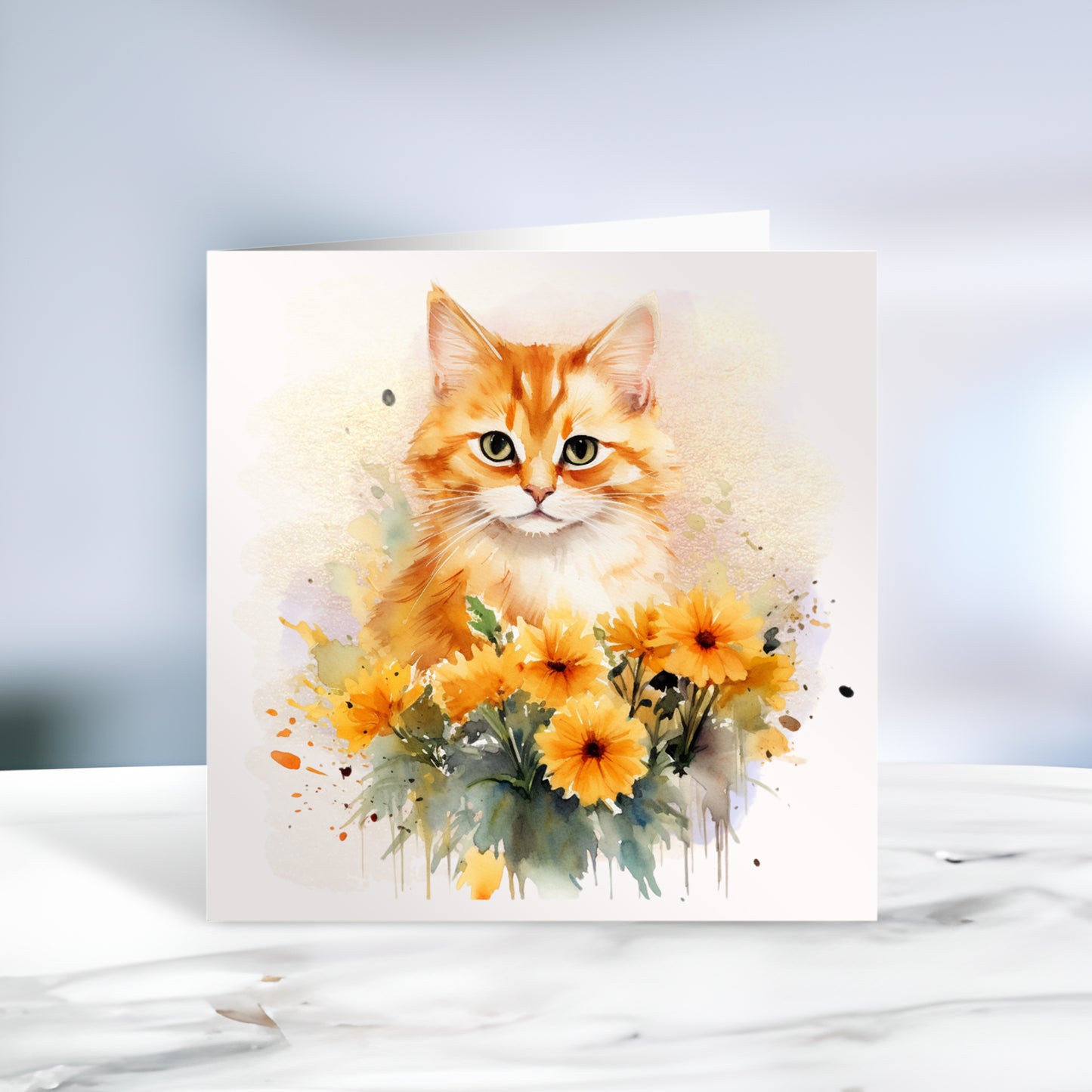 Ginger and white cat sat among orange flowers on a white card. The card is placed on a grey marble surface.