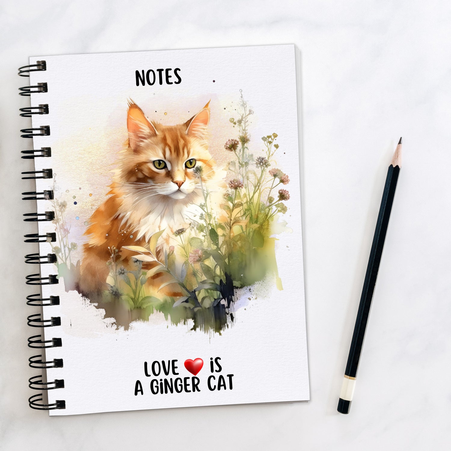 A white spiral bound notebook showing a long haired ginger cat with a white front sat amongst the grass and wildflowers. A quote is seen at the bottom of the book and a pencil is laid to the side.