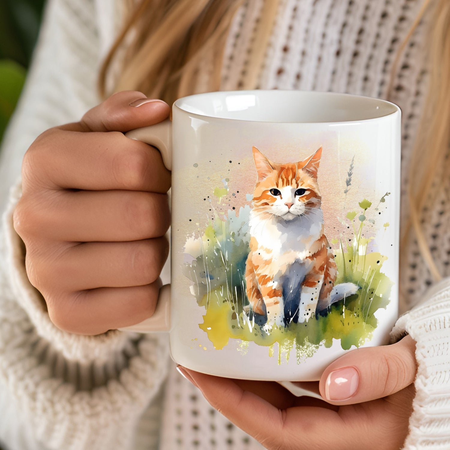 Woman holding a white ceramic mug showing a ginger cat sat on grass.