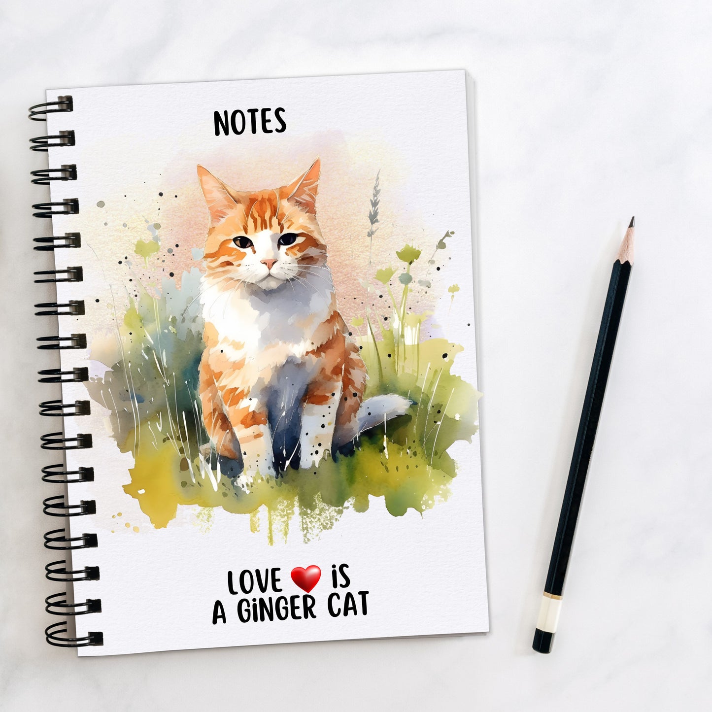 A white spiral bound notebook showing a ginger cat with a white front sat amongst the grass. A quote is seen at the bottom of the book and a pencil is laid to the side.