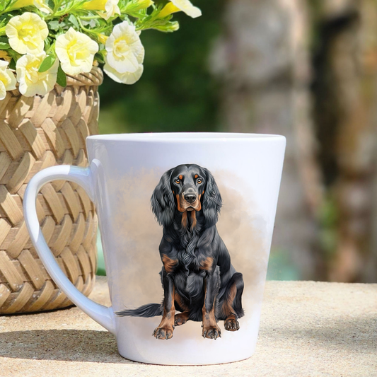 A white ceramic latte mug featuring a  Gordon Setter in a misty background.  A basket containing yellow flowers sits to the left-hand side.