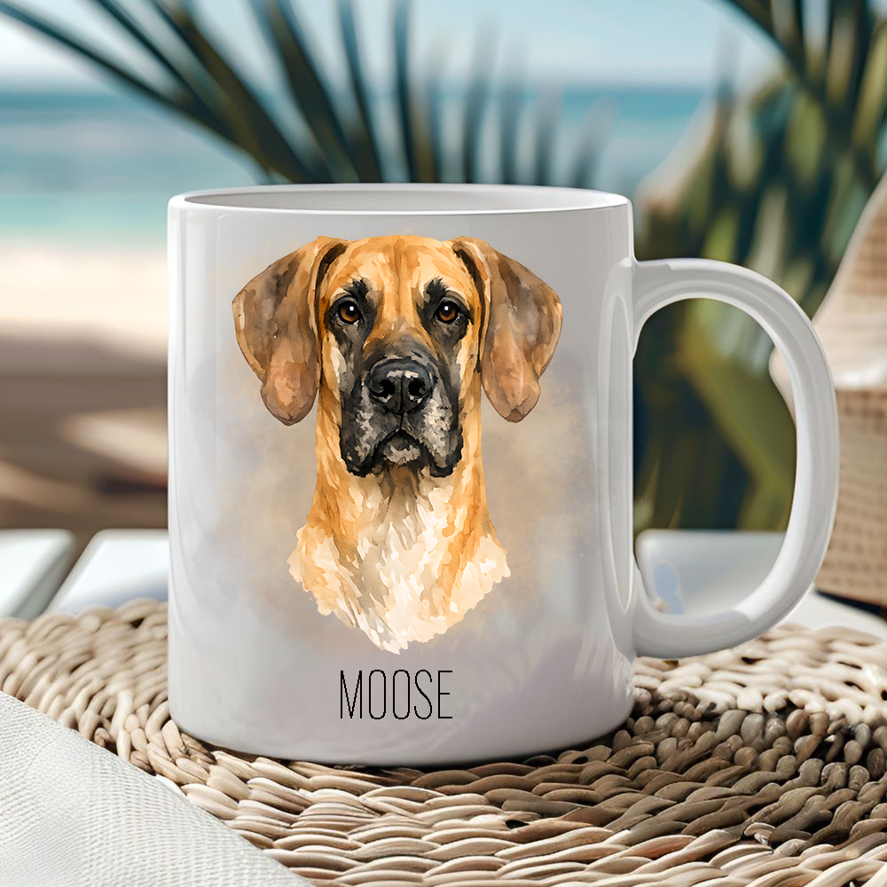 White ceramic mug showing a Fawn Great Dane with gold/brown smoke effect background.  Mug is placed on a wicker mat  and a seascape sits behind.