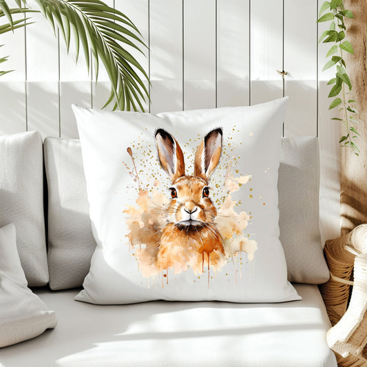 A brown Hare head and shoulders image with a splattered and smoky background on the front of a white cushion which is placed on a cream sofa.  White panels and green fern create the background.