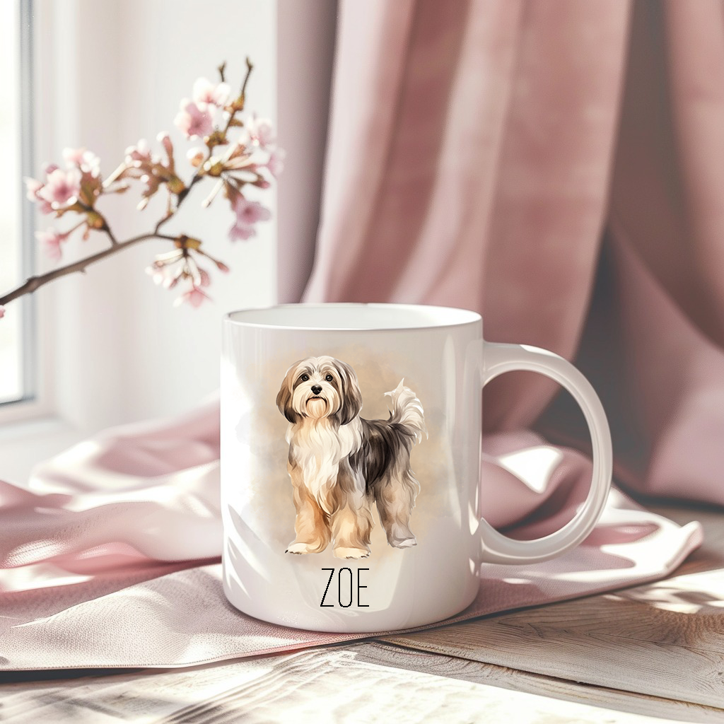 A beautiful Havanese dog is in a standing position on a white ceramic mug which has been placed on a pink drape.  The mug is personalised and a stem of small pink flowers accessorizes the image.